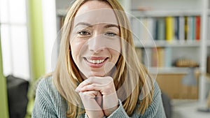 Young blonde woman student sitting on table smiling at library university