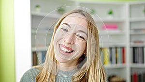 Young blonde woman student smiling confident standing at library university