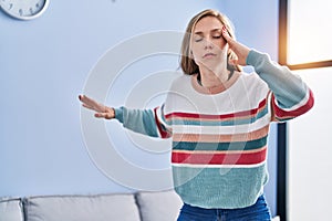 Young blonde woman suffering dizzy standing at home