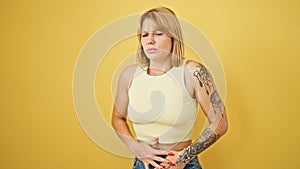 Young blonde woman suffering for stomach ache standing over isolated yellow background