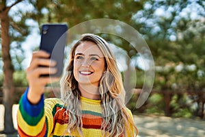 Young blonde woman taking selfie picture at the park