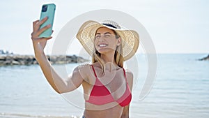 Young blonde woman tourist wearing bikini make selfie by smartphone at beach