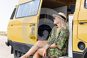 Young blonde woman travelling by campervan at the seaside