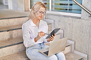 Young blonde woman using laptop and touchpad at street