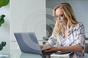 young blonde woman using laptop while working