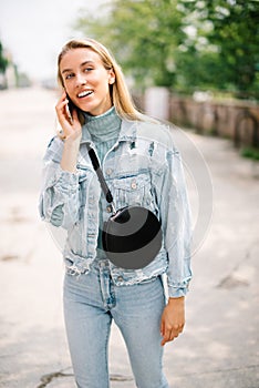 Young blonde woman using phone in a city.