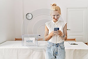 Young blonde woman using smartphone smiling at electoral college