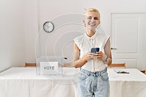 Young blonde woman using smartphone smiling at electoral college