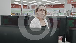 A young blonde woman walks through an electronics hypermarket and chooses a TV.