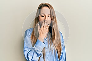 Young blonde woman wearing casual blue shirt bored yawning tired covering mouth with hand