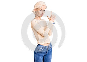 Young blonde woman wearing casual clothes holding symbolic gun with hand gesture, playing killing shooting weapons, angry face