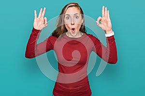 Young blonde woman wearing casual clothes looking surprised and shocked doing ok approval symbol with fingers