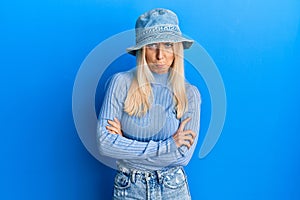 Young blonde woman wearing casual denim hat skeptic and nervous, disapproving expression on face with crossed arms