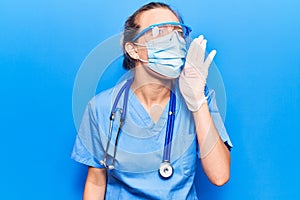 Young blonde woman wearing doctor uniform and coronavirus protection holding help reminder shouting and screaming loud to side