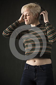 Young blonde woman wearing headphones and enjoying the music.