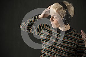 Young blonde woman wearing headphones and enjoying the music.