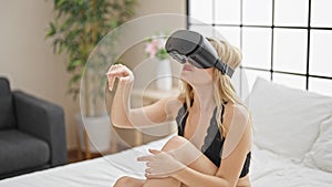 Young blonde woman wearing lingerie using virtual reality glasses at bedroom