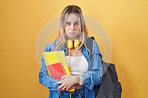 Young blonde woman wearing student backpack and holding books depressed and worry for distress, crying angry and afraid