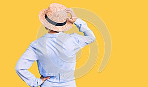 Young blonde woman wearing summer hat backwards thinking about doubt with hand on head