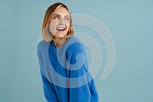 Young blonde woman wearing sweater smiling and looking aside