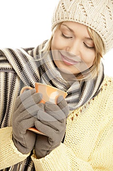 Young blonde woman wearing winter outfit drinking hot beverage