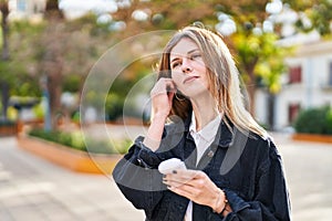 Young blonde woman wearing wireless earphones at park