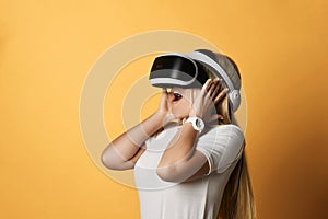 Young blonde woman in white t-shirt and VR glasses is amazed by modern augmented virtual reality technology