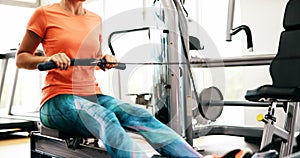 Young blonde woman working on rowing machine