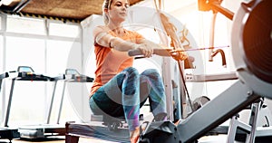 Young blonde woman working on rowing machine