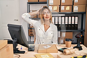 Young blonde woman working at small business ecommerce confuse and wonder about question