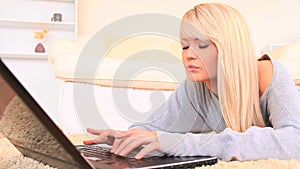 Young blondhaired woman chatting on her laptop