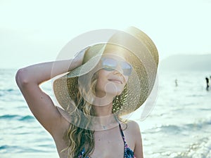 Young blondy girl in sunglasses and straw hat at the beach photo