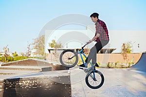 Young bmx biker doing trick, training in skatepark