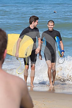 Young bodyboarders coming out ocean