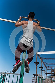 Young bodybuilder doing pull up exercise on bar