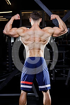 Young bodybuilder with great muscles posing in gym