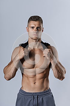 Young bodybuilder showing his muscular body against gray background