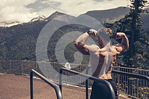 Young bodybuilder showing muscles shape outdoors