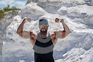 Young bodybuilder with srong muscles. Strong muscular man showing power outdoor.