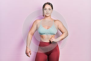 Young bodybuilder woman posing showing muscles standing wearing workout outfit