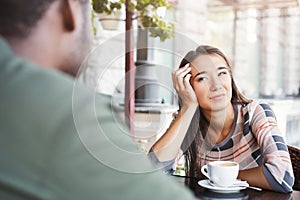 Young bored girl drinking coffee on date at a cafe