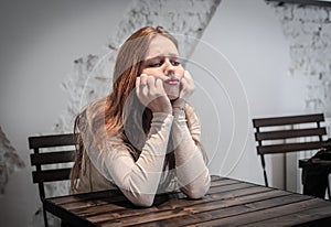 Young bored woman sitting at a table waiting