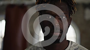 Young boxer with boxing pear on background looking to the camera