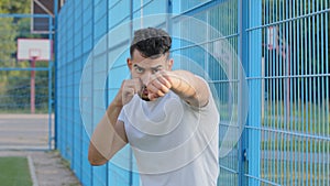 Young boxer, fighter, wrestler or football fan waving hands with clenched fists, Arabic Hispanic male athlete shows blow