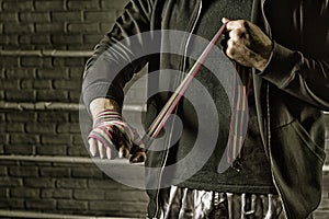 Young boxer preparing for fight, wrapping hands with bandage, copy space