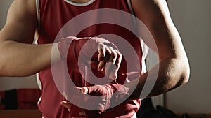 The young boxer pulls red bandage on hands and fight poses