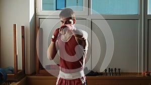 The young boxer pulls red bandage on hands and start boxing