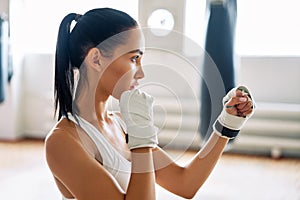 Young boxer woman posing in combat stance in gym