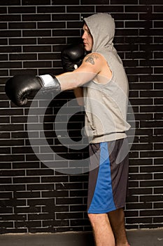 Young boxer working out against a brick wall