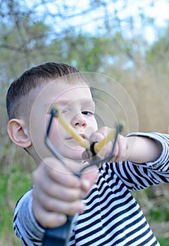 Young Boy Aiming Sling Shot at Camera